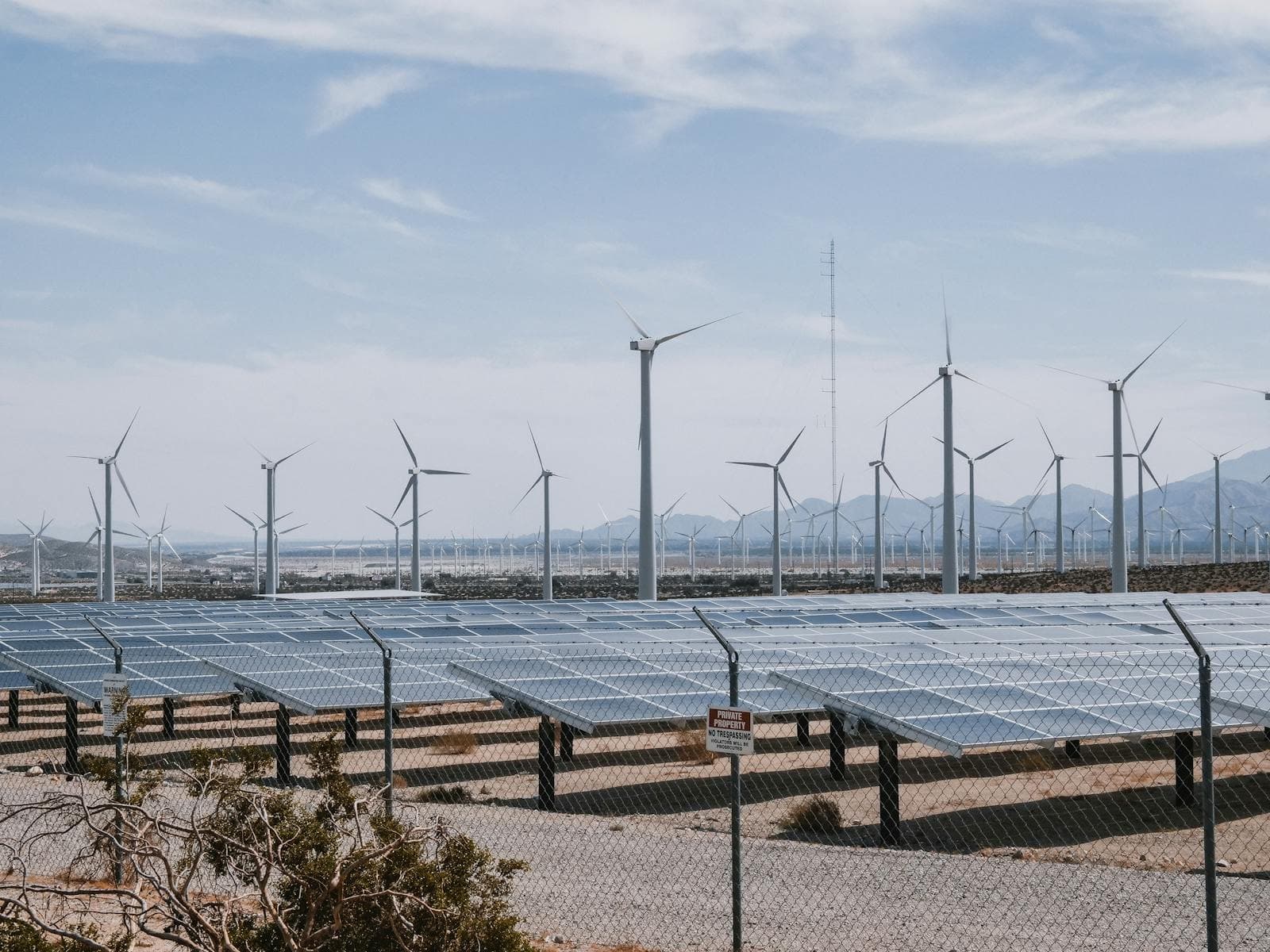 Wind turbines and solar panels under a clear sky.