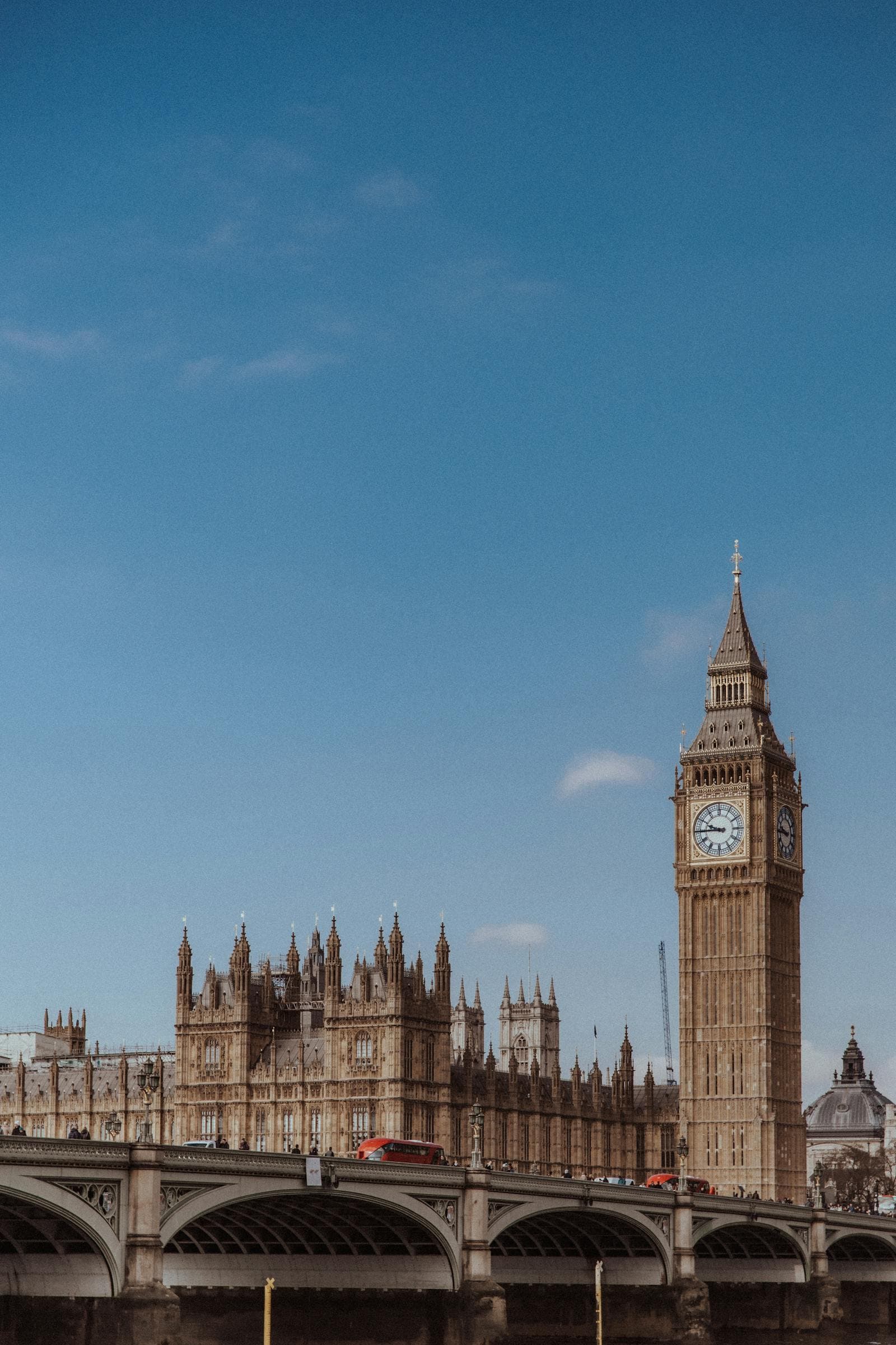 Big Ben and Westminster Bridge under a blue sky in London.