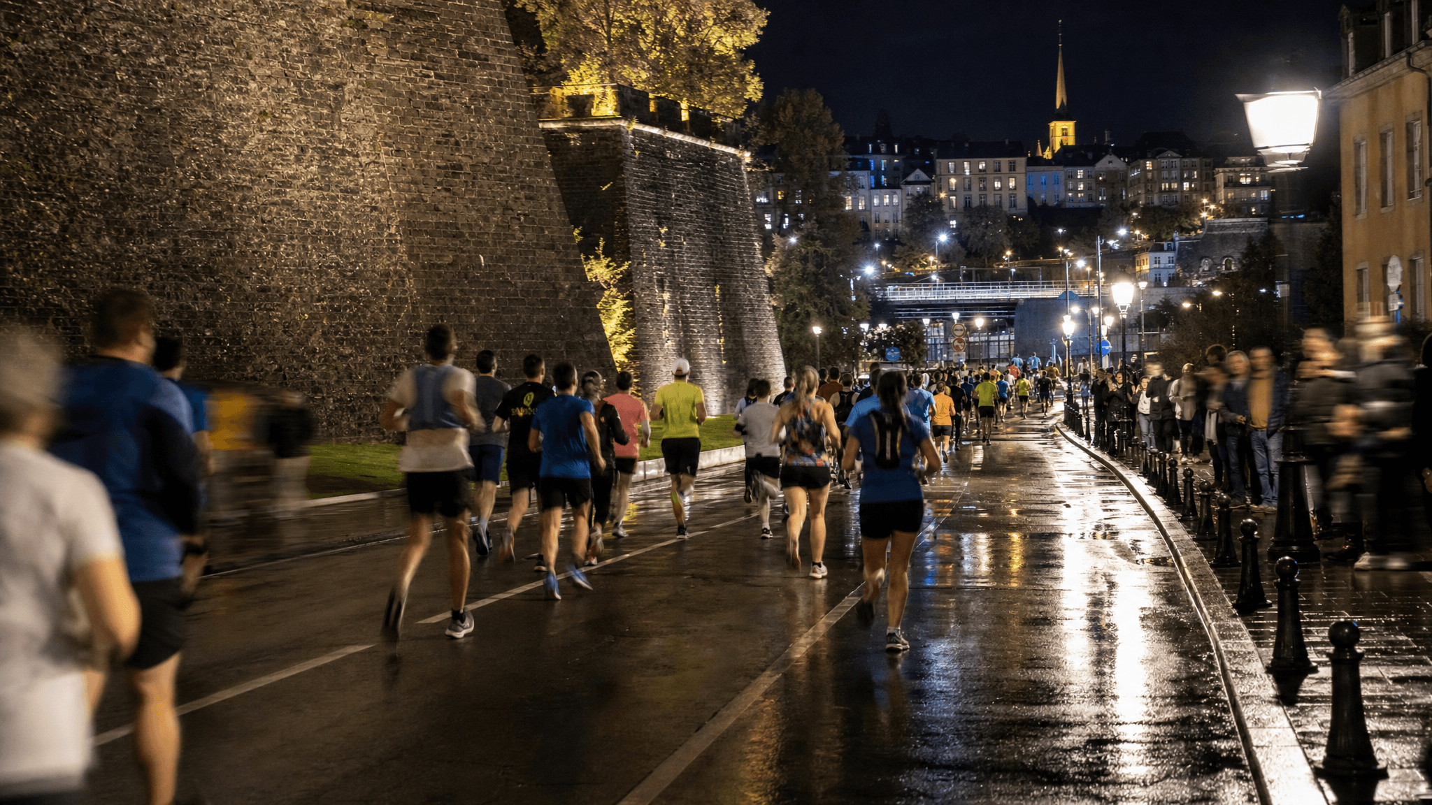 Night runners on wet Luxembourg City streets during a marathon event.